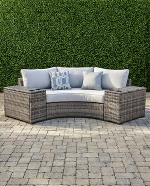 Montauk Curve outdoor 3-piece small space sectional — curved gray wicker loveseat with a drink-holder console on each side, on a paver patio — view 1