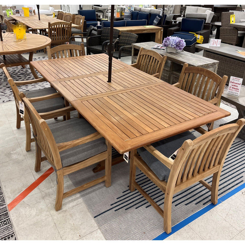 Bali solid teak extendable dining table with six Tista armchairs and navy cushions on the showroom floor