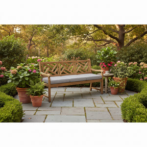 Alor solid teak 60-inch 3-seat outdoor bench with criss-cross lattice back on a garden patio, shown with its full-length light gray all-weather cushion — view 1
