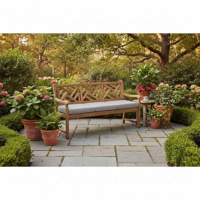 Alor solid teak 60-inch 3-seat outdoor bench with criss-cross lattice back on a garden patio, shown with its full-length light gray all-weather cushion