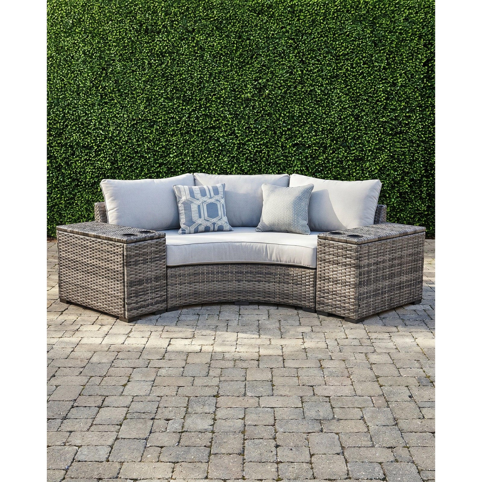 Montauk Curve outdoor 3-piece small space sectional — curved gray wicker loveseat with a drink-holder console on each side, on a paver patio