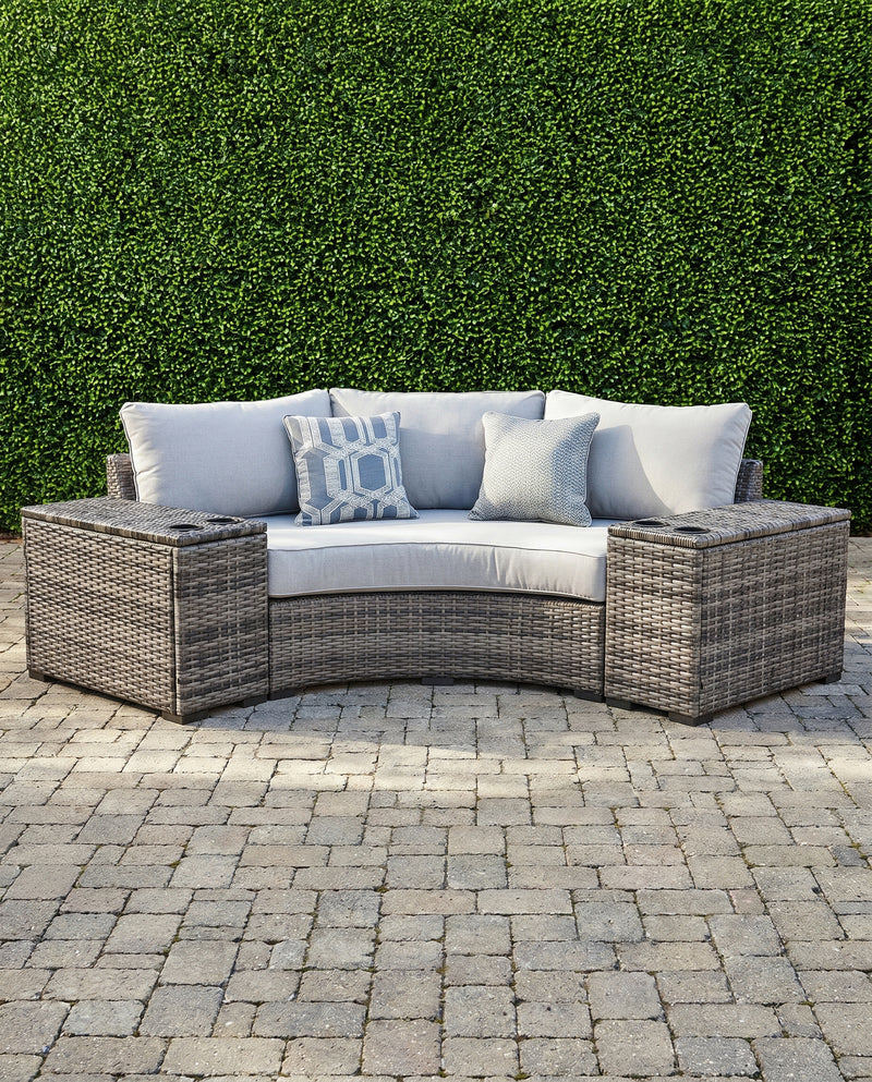 Montauk Curve outdoor 3-piece small space sectional — curved gray wicker loveseat with a drink-holder console on each side, on a paver patio
