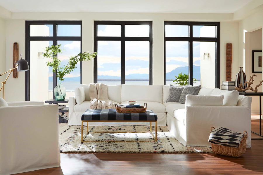 White slipcovered custom sectional in front of a wall of windows overlooking the water