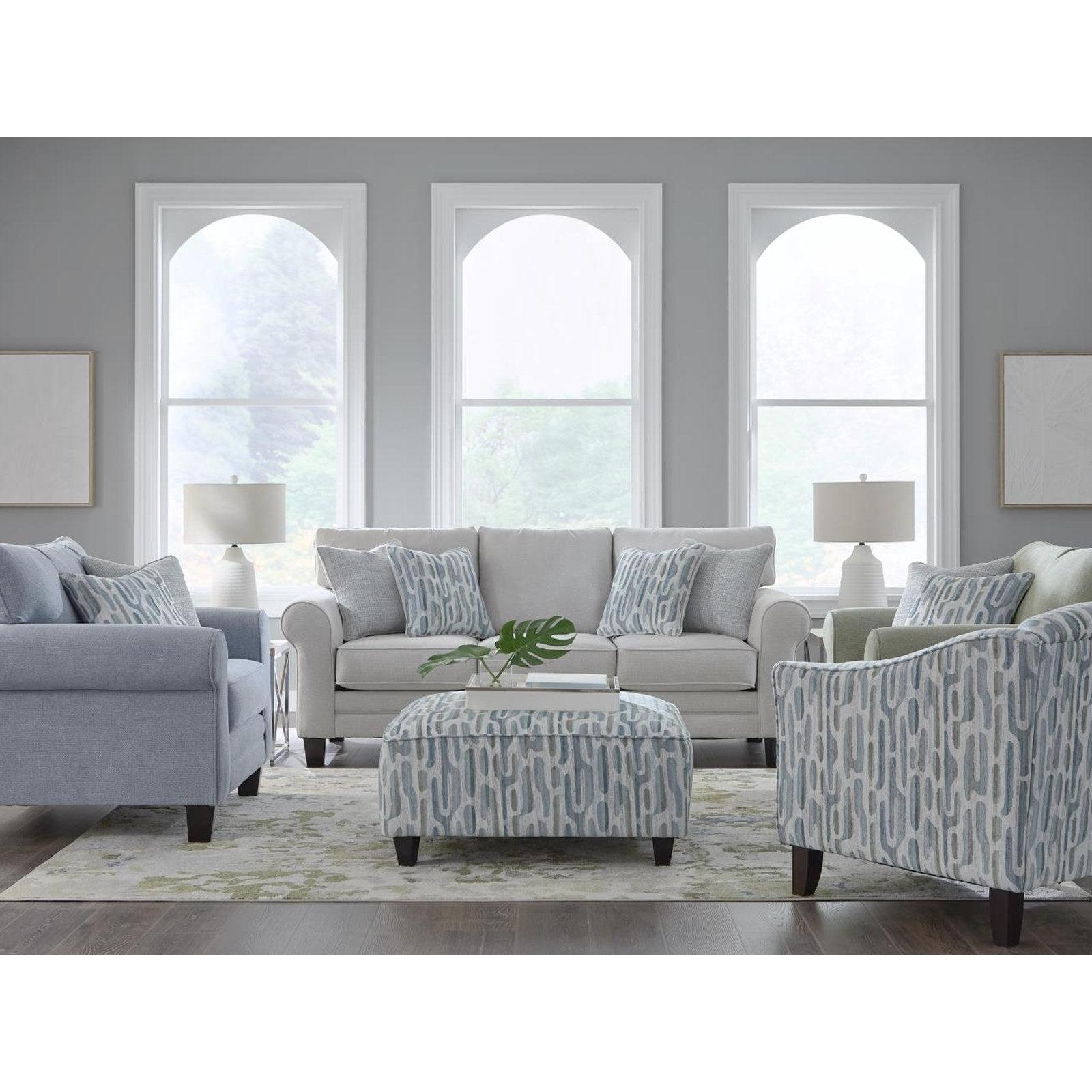 Locust Valley sofa in dove grey with a French blue chair, sage chair and printed cocktail ottoman in a light living room
