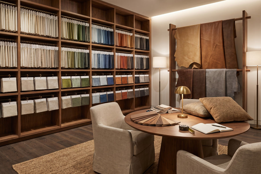 Design resource area: a wall of fabric samples arranged by color, leather hides on rails, and a consultation table with wood finish samples