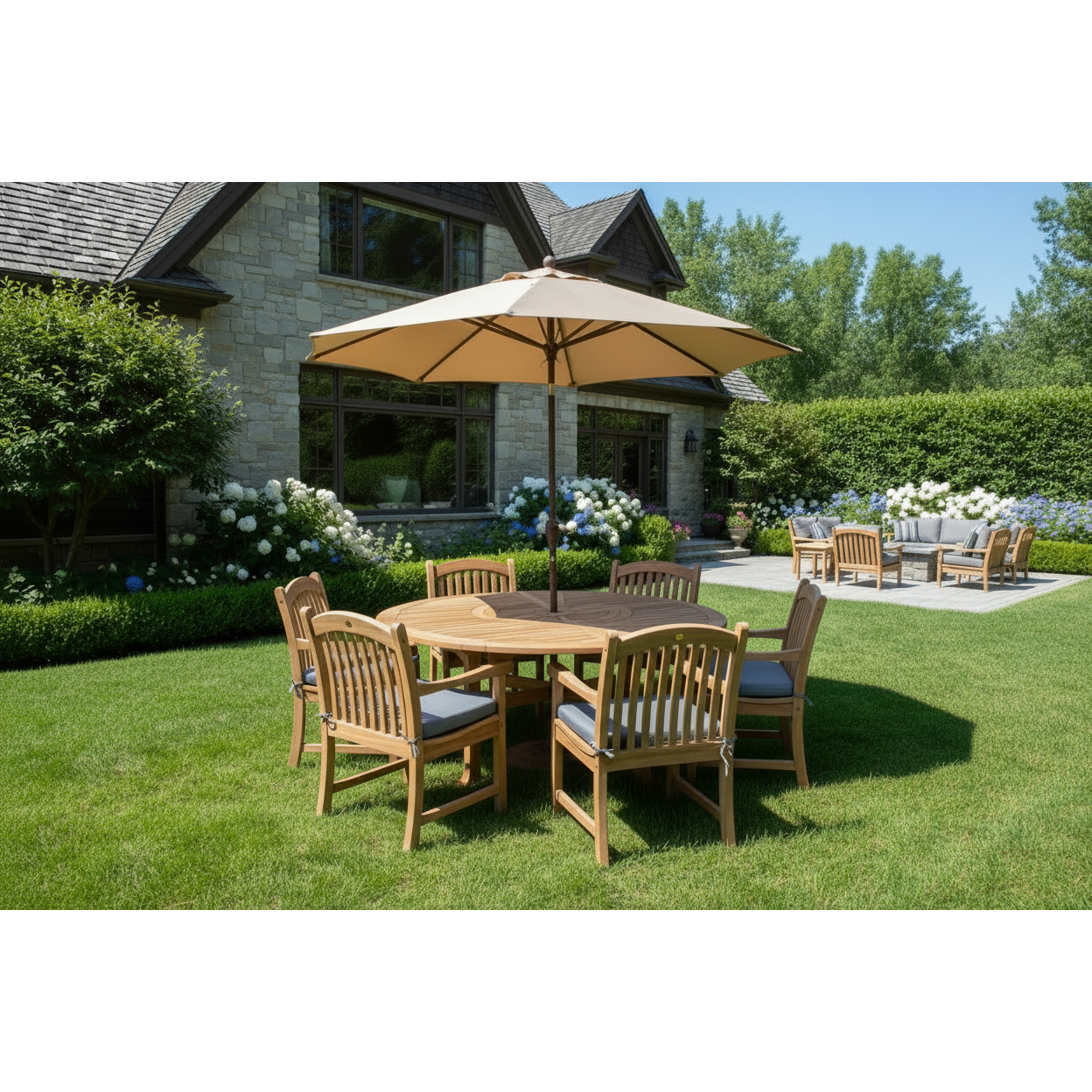 Komodo round teak dining set with tan market umbrella on a backyard lawn