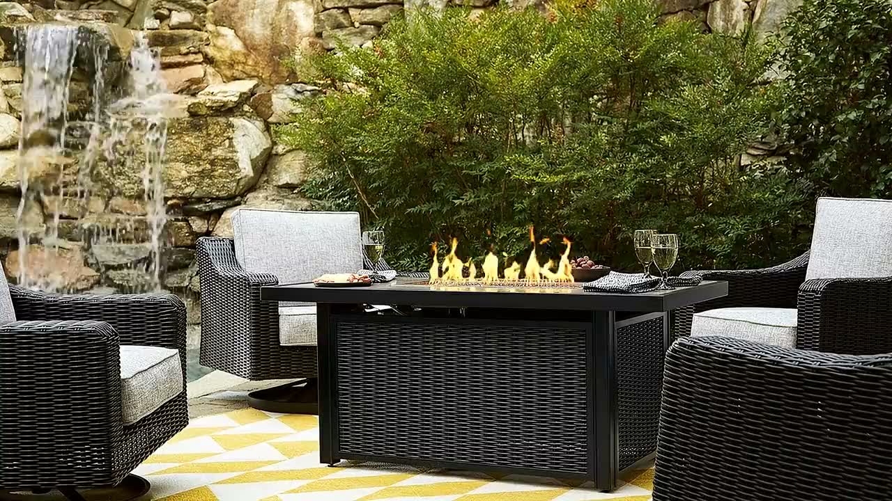 Fire Island fire pit table with swivel chairs beside a waterfall